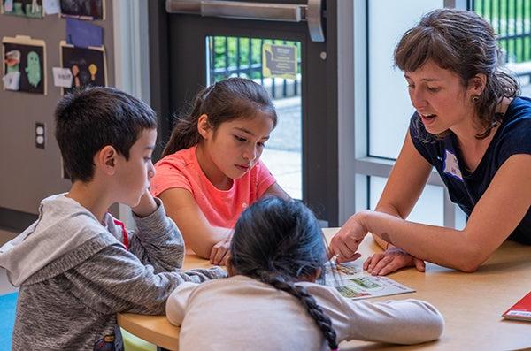 一位老师和三个年轻的学生坐在一张桌子旁谈话.