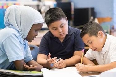 Three students work together in a classroom
