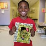 一个年轻的学生举起一件学生的作品，微笑着拍照